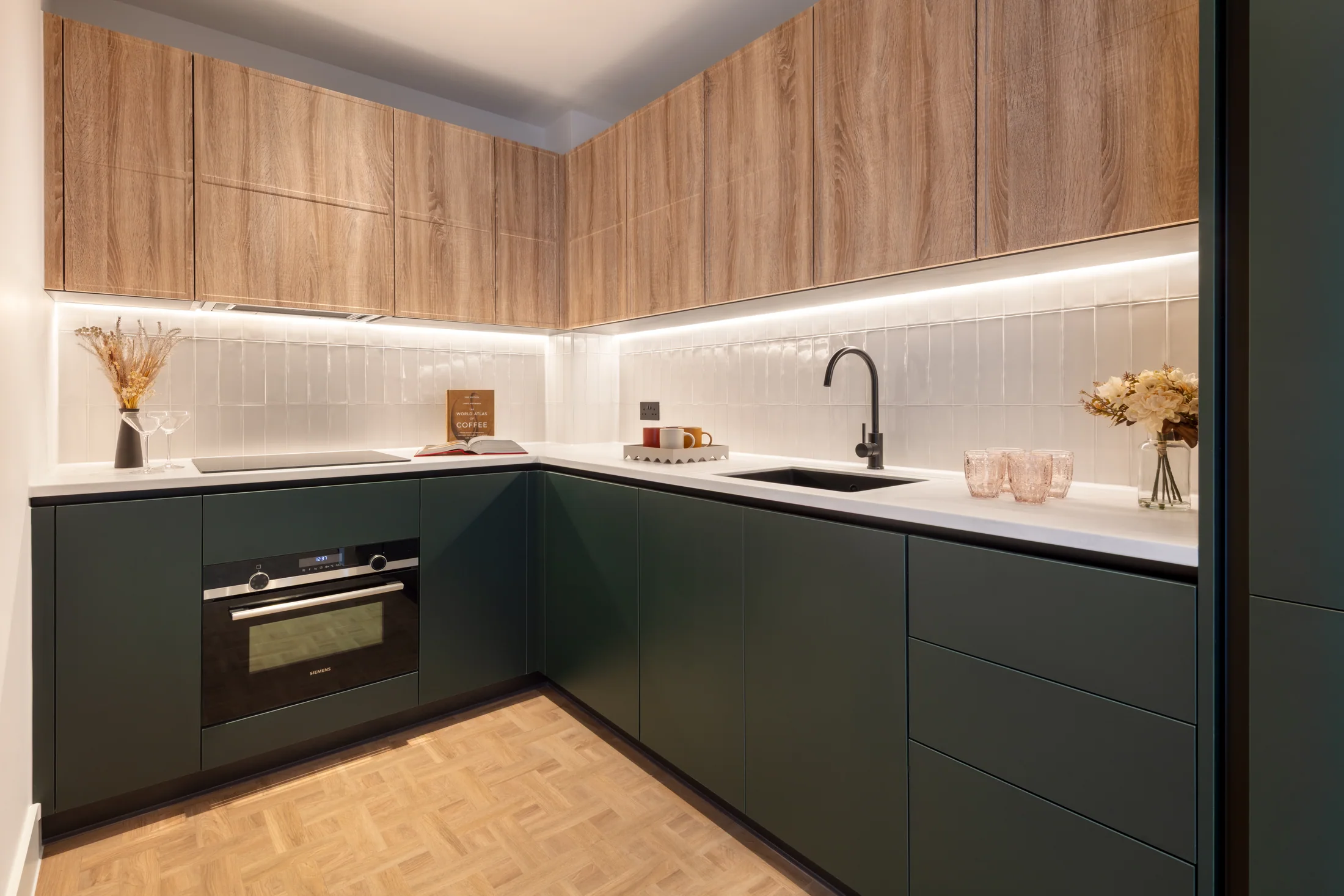 One Clapham existing fitted kitchen with deep green cabinetry and warm wood grain upper cupboards