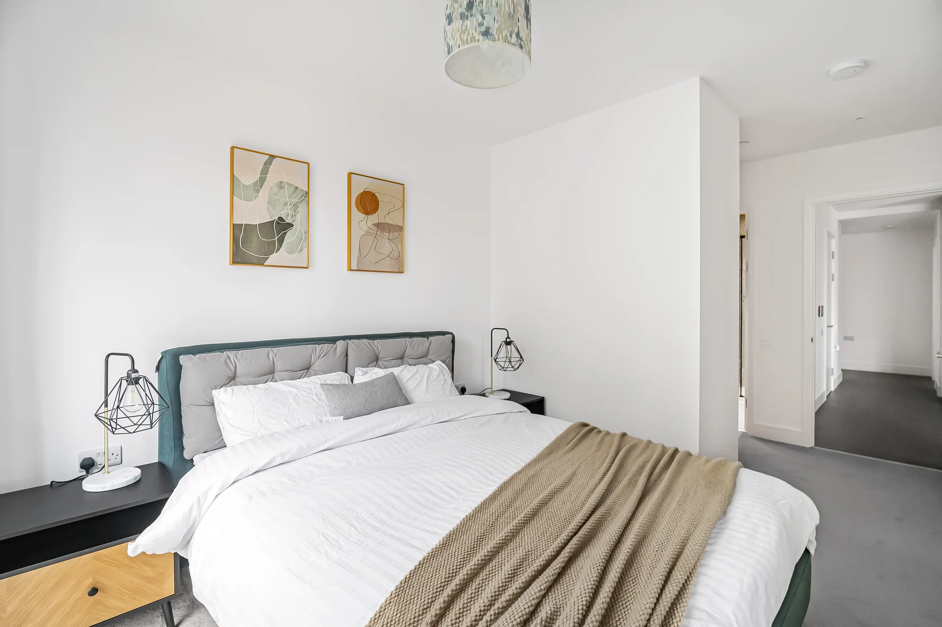 Finished main bedroom at Hawksbury Heights, with neutral furnishings, upholstered bed and two bedside lamps