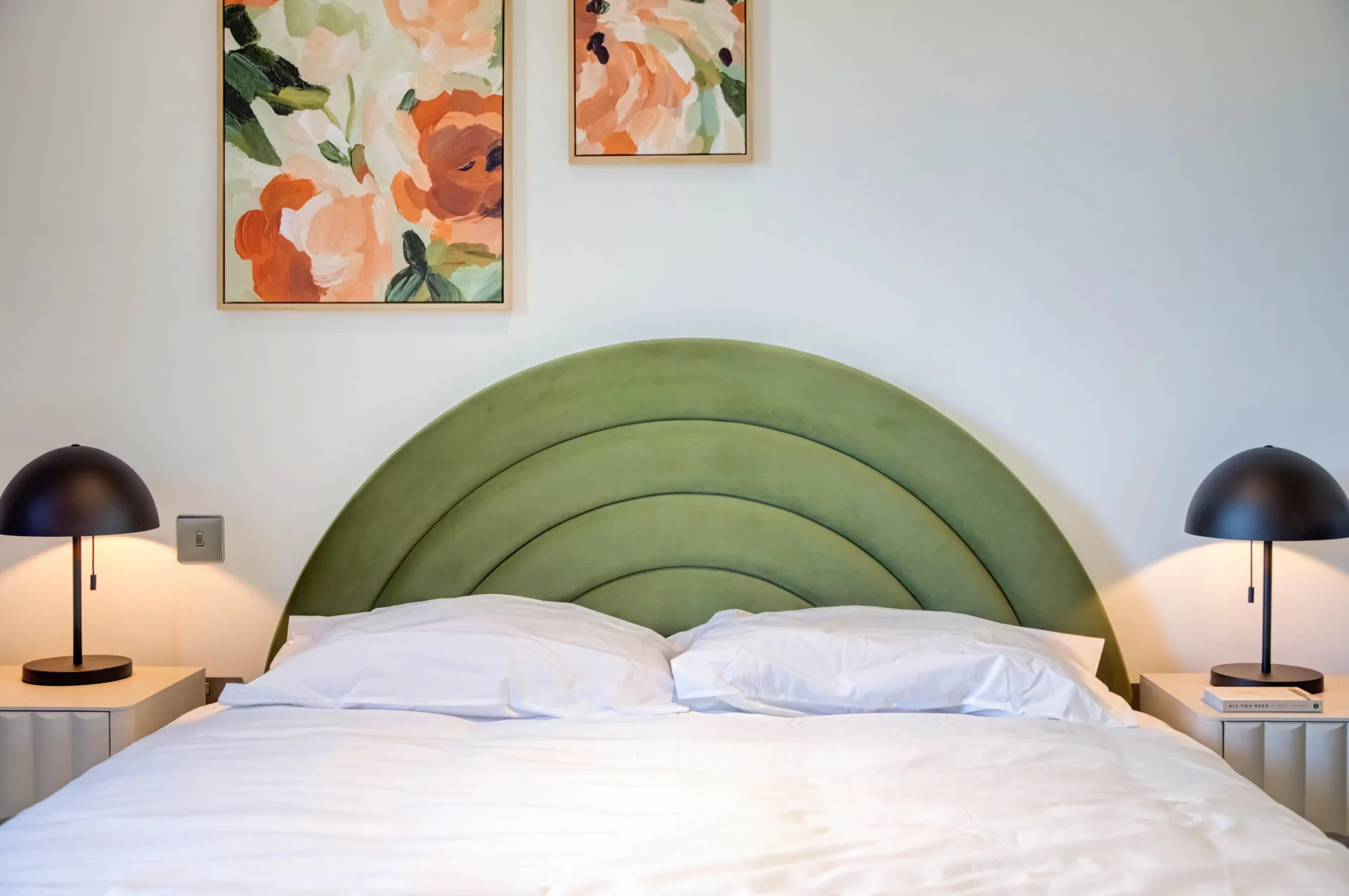 Green upholstered bed and colourful art at a completed Pilot Walk interior